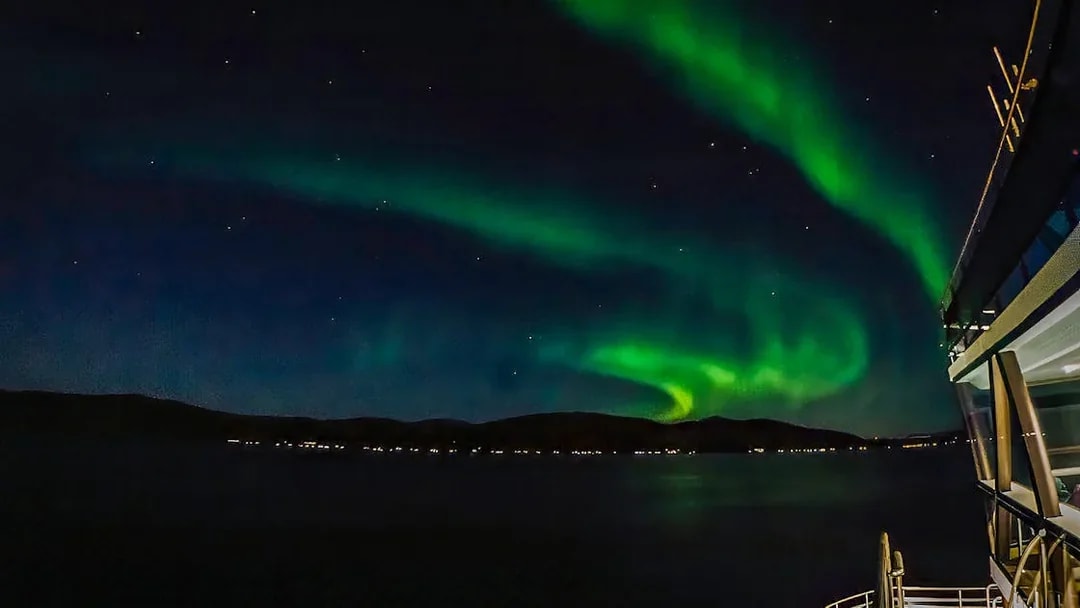 Northern lights over a cruise ship deck at night.