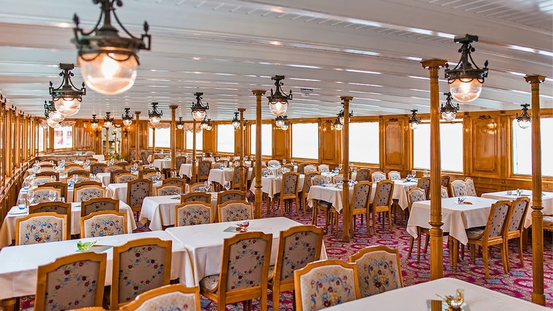 Elegant dining area on a cruise ship in the Riviera region, featuring wooden decor and set tables.
