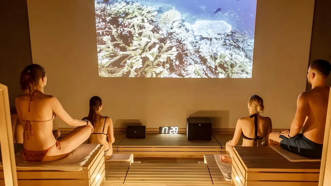 Visitors relaxing in a sauna at Therme Bucuresti Spa, watching an underwater video.