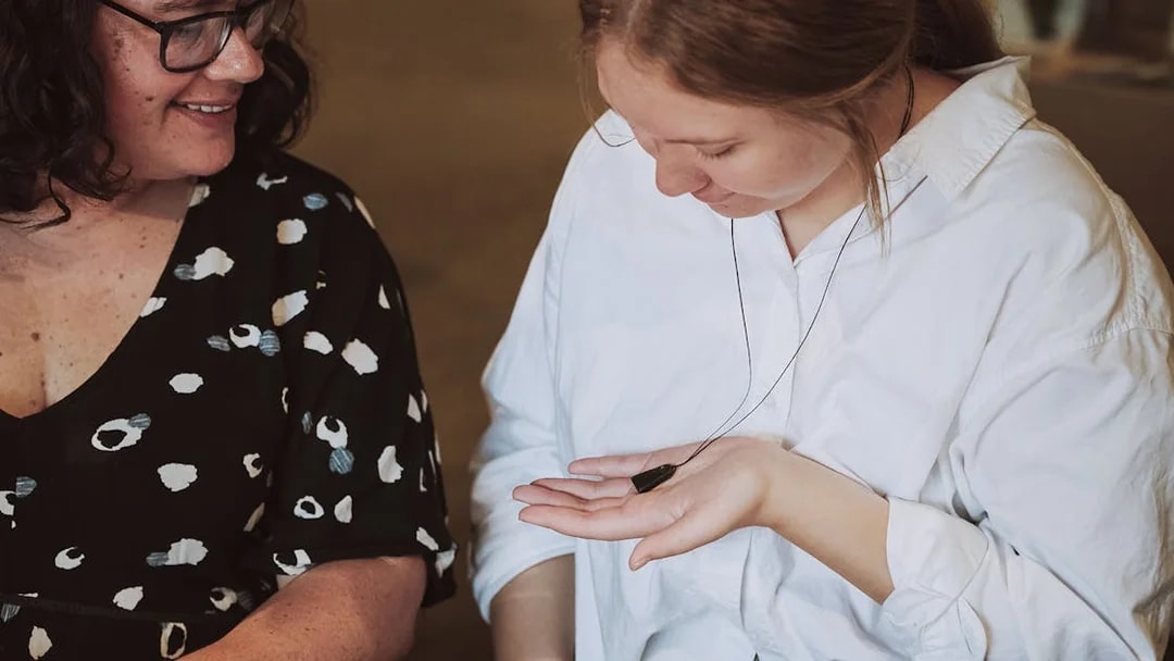 Two people examining a jade pendant during the Mountain Jade Highlights Tour.