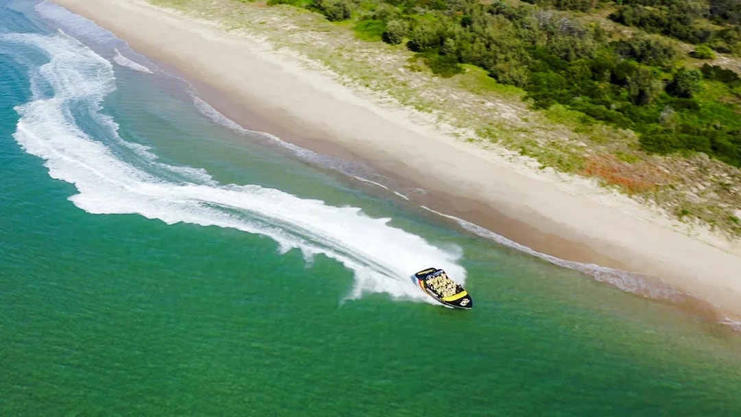 Jet boat speeding along Gold Coast shoreline during 55-minute adventure ride.