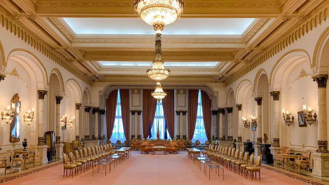 Grand hall with chandeliers and ornate decor inside Palace of Parliament, Bucharest.