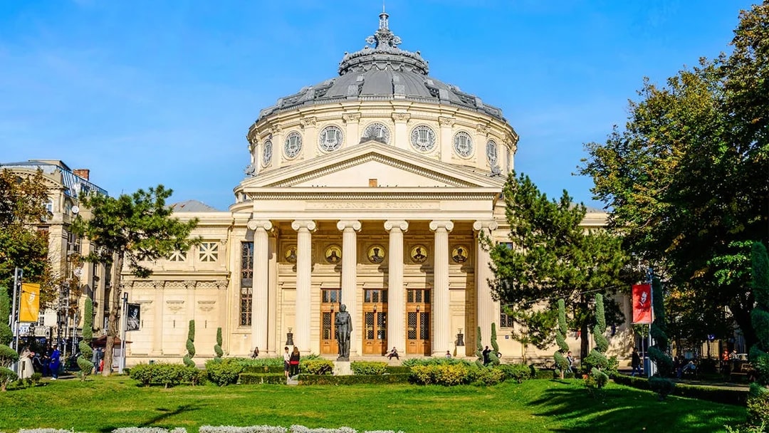 Athenaeum in Revolution Square, Bucharest, with neoclassical columns and garden in foreground.