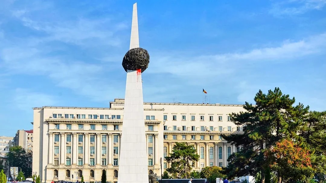 Memorial of Rebirth monument in Revolution Square, Bucharest, with surrounding buildings.