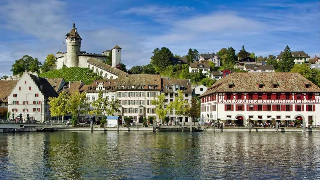 Laufen Castle overlooking Rhine Falls with traditional Swiss buildings in the foreground.
