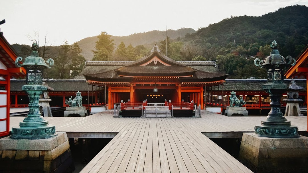 Itsukushima Shrine in Hiroshima, Japan, with traditional architecture and surrounding mountains.