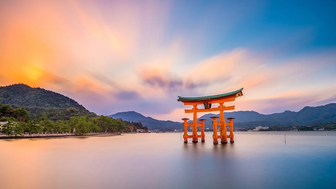 Torii gate at Itsukushima Shrine in Hiroshima during sunset, viewed from the water.