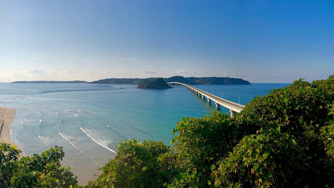 Bridge over turquoise sea in Yamaguchi, Japan, viewed from a lush green hill.