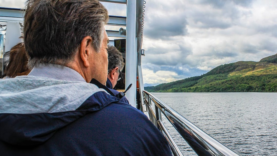 Passengers enjoying scenic views from a cruise on a lake with hills in the background.