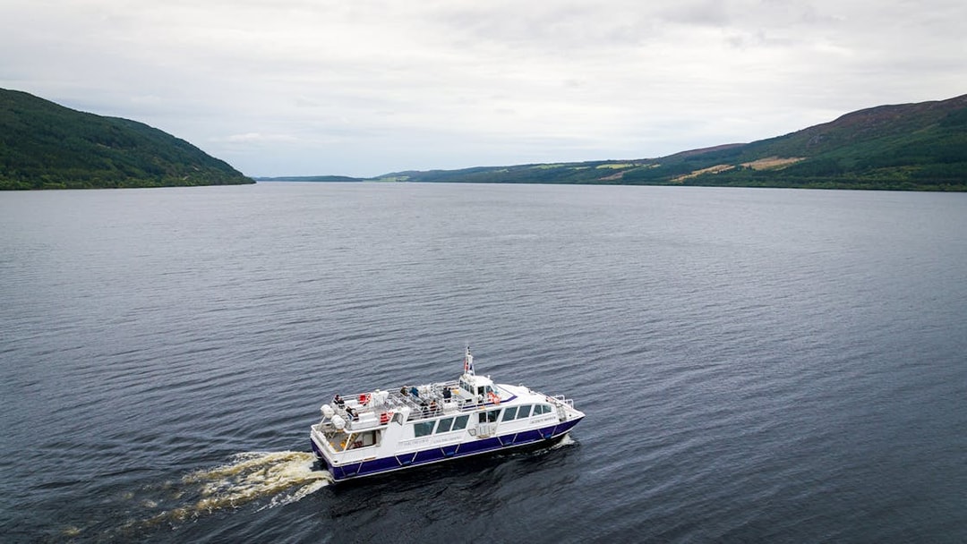 Tourist boat cruising on Loch Ness with scenic hills in the background.