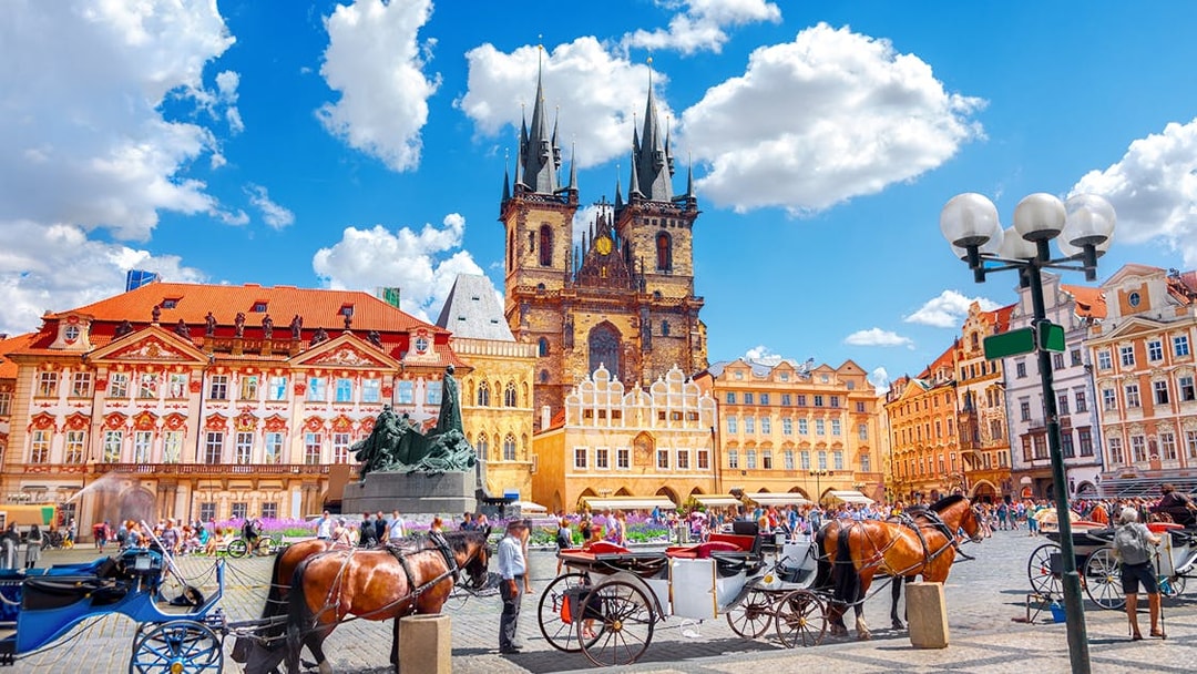 Horse-drawn carriages in Old Town Square, Prague, with Týn Church in the background.