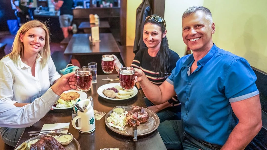 Group enjoying traditional Czech meal and beer during Prague city tour lunch cruise.
