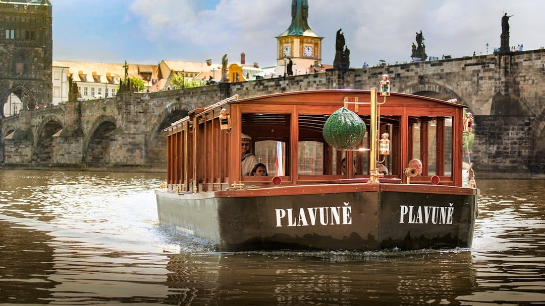 Boat cruising on the Vltava River with Charles Bridge in Prague.