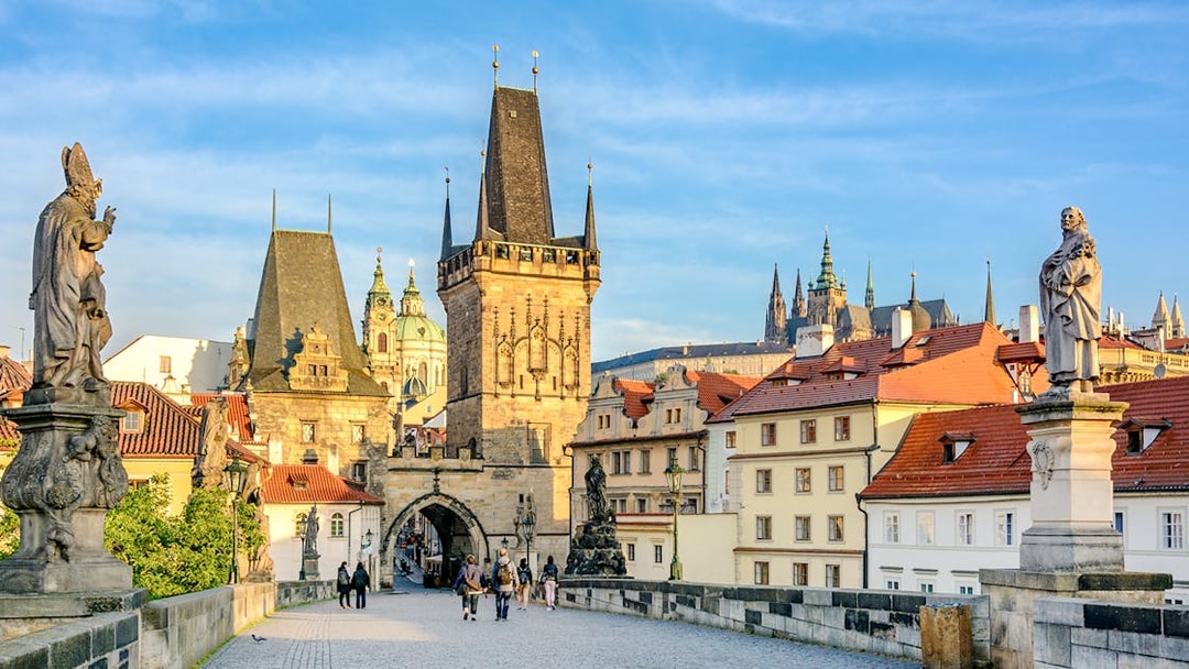 Charles Bridge in Prague with statues and Gothic towers in the background.