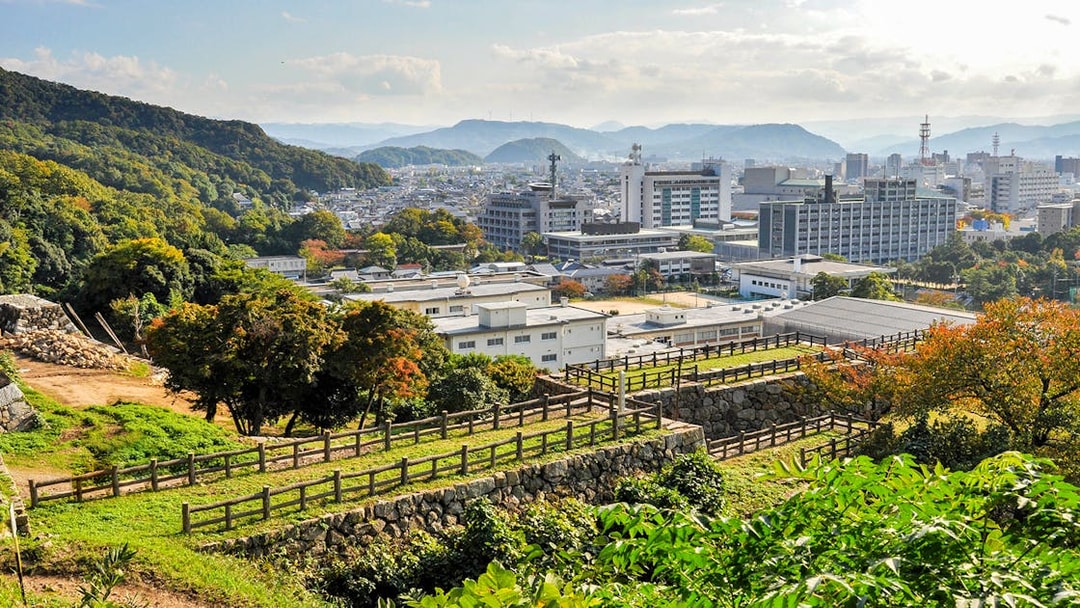 View of Okayama cityscape with surrounding hills, seen from a historic site, Japan.