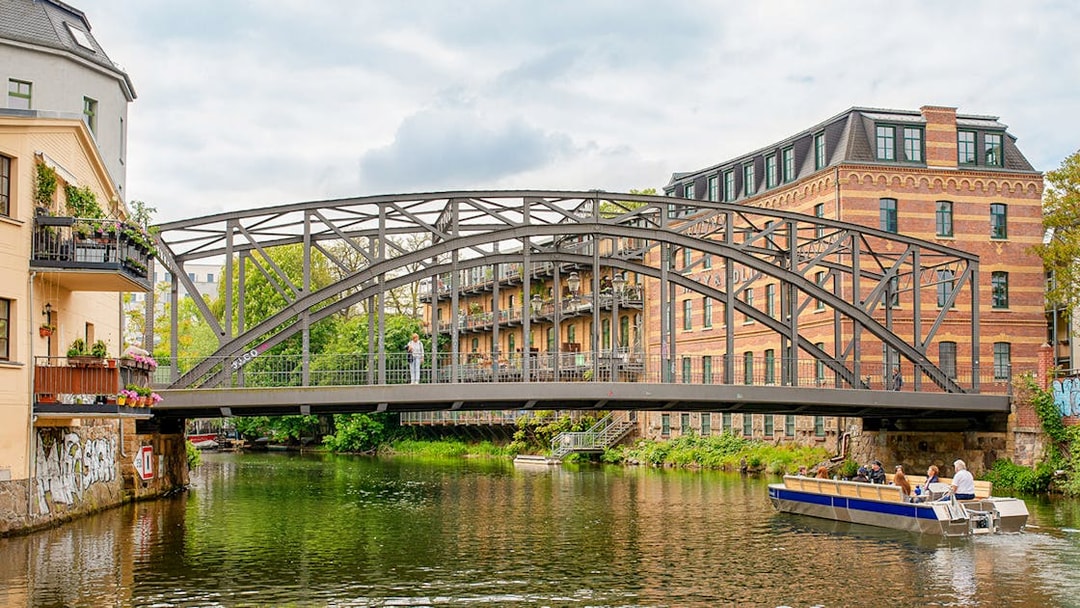 Motorboat tour on Karl Heine Canal in Leipzig passing under a historic bridge.