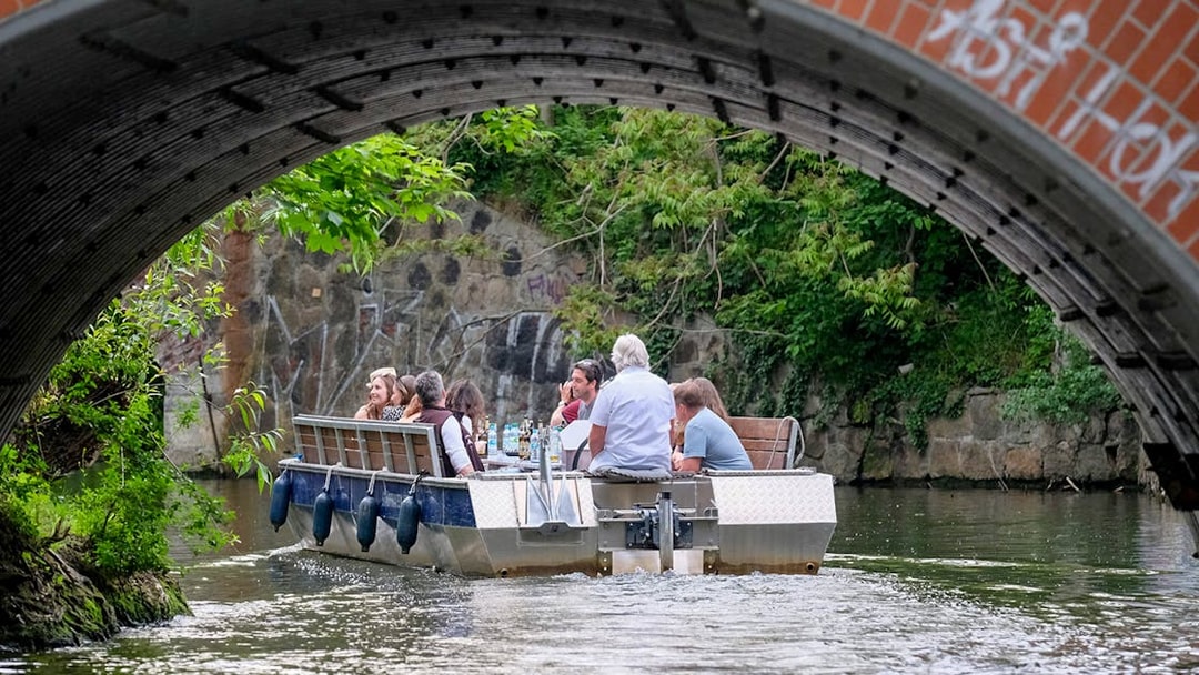 Guests on a motorboat tour under a bridge on Karl Heine Canal, Leipzig.