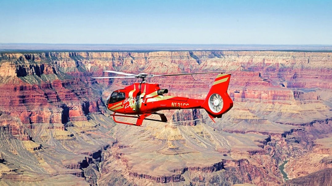 Red helicopter flying over the Grand Canyon.