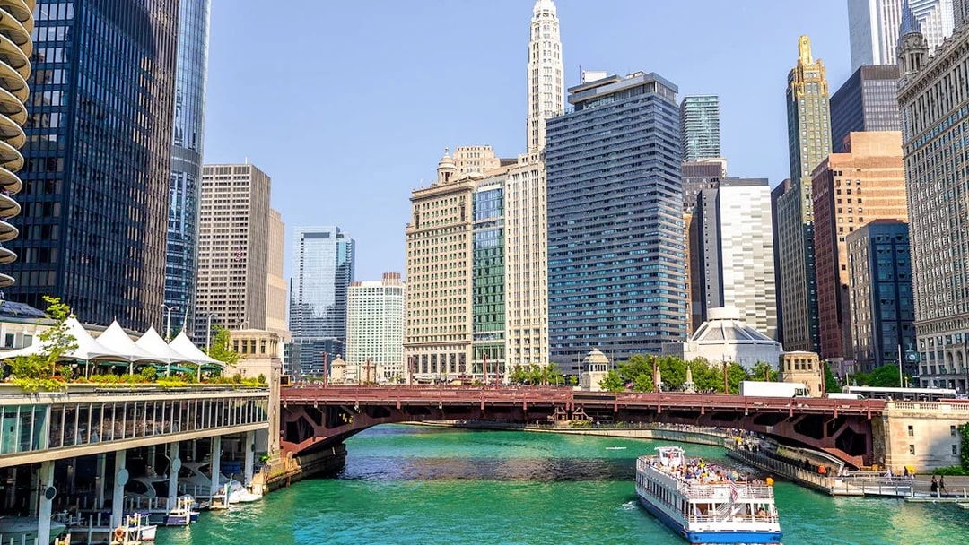 Cruise boat on Chicago River with city skyscrapers in the background.