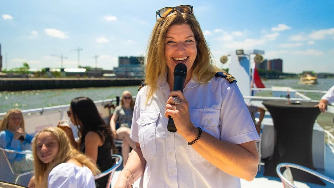 Live guide speaking on a River Cruise in Rotterdam with passengers in the background.