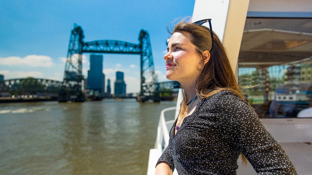 Guest enjoying a river cruise in Rotterdam with the iconic bridge in the background.
