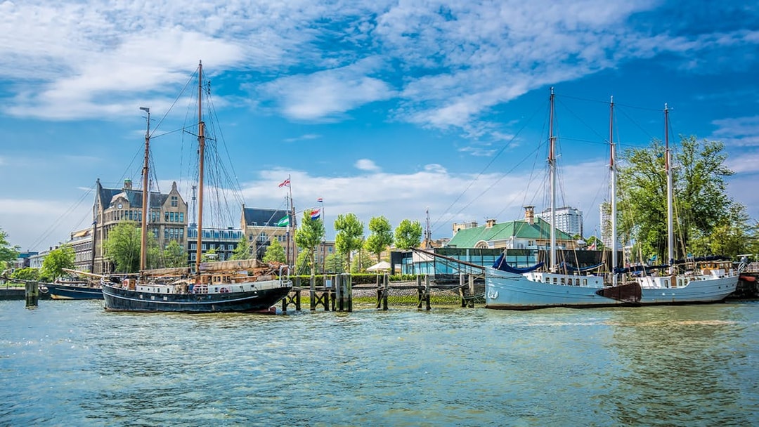 Sailboats docked at Veerhaven harbor in Rotterdam, Netherlands, with historic buildings in the background.