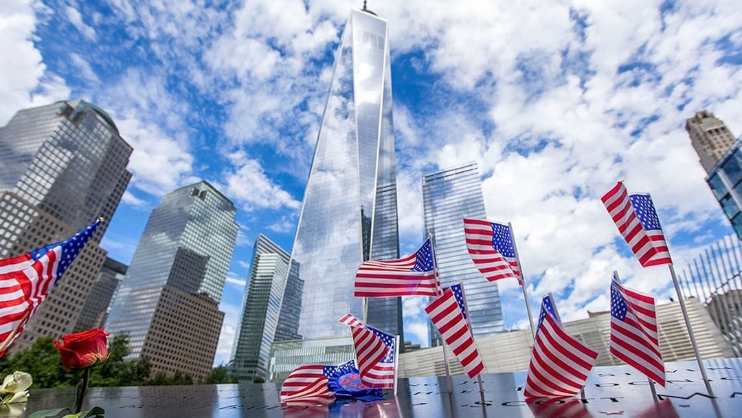 USA flags at 9/11 Memorial with One World Trade Center in New York City.