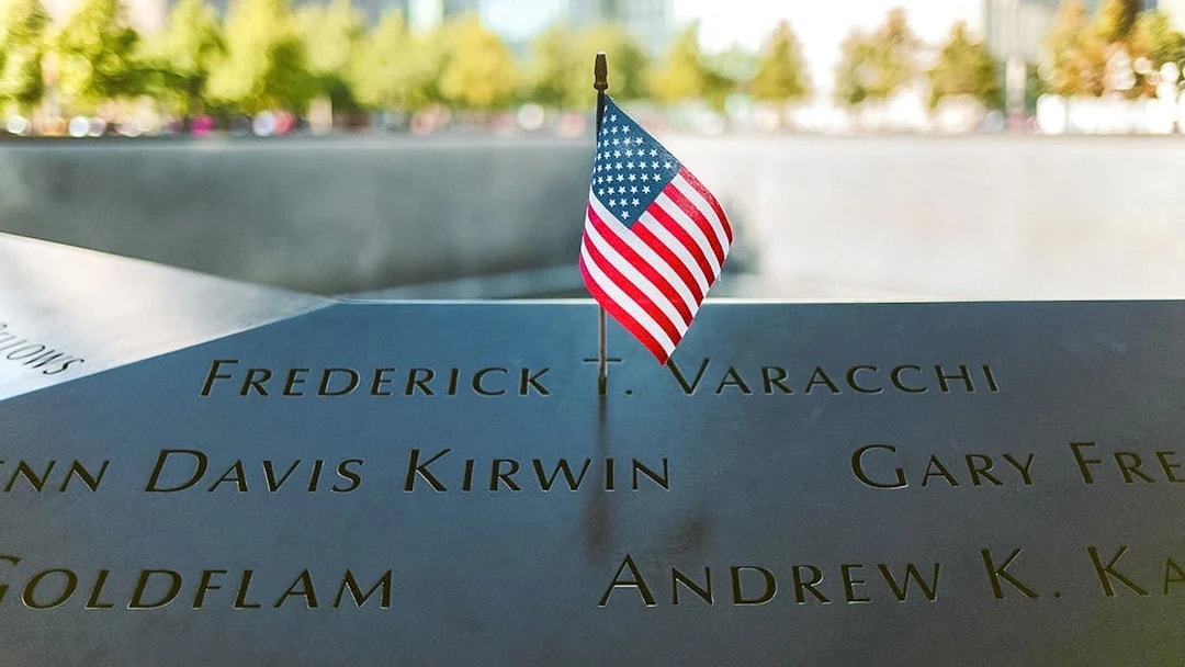 Names engraved at 9/11 Memorial with small American flag, New York City.