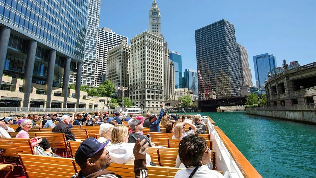 Visitors on Chicago River cruise viewing city architecture.
