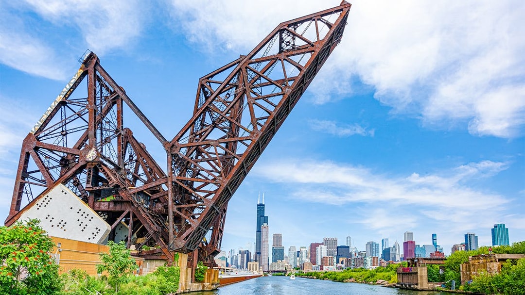 Chicago skyline with Willis Tower viewed from the river, featuring a raised railway bridge.