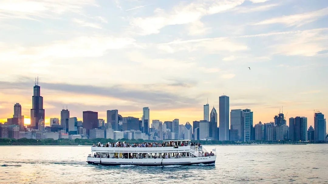Cruise boat on Lake Michigan with Chicago skyline at sunset.