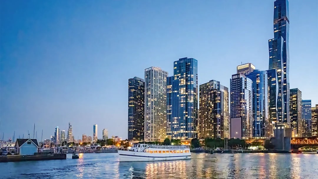 Downtown Chicago skyscrapers at sunset with a cruise boat on Lake Michigan.