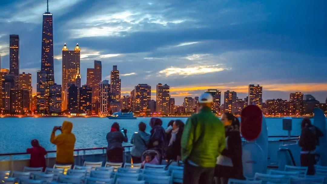 Cruise passengers view Chicago skyline at sunset on Lake Michigan.