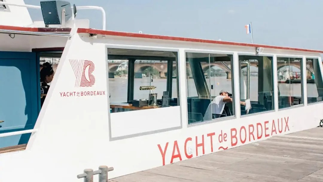 Yacht docked for Bordeaux River Cruise with bridge in background.