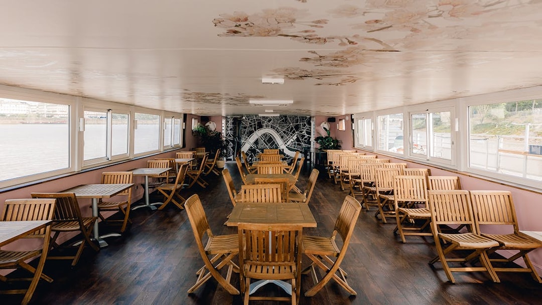 Interior seating area of Bordeaux River Cruise with wooden tables and chairs.