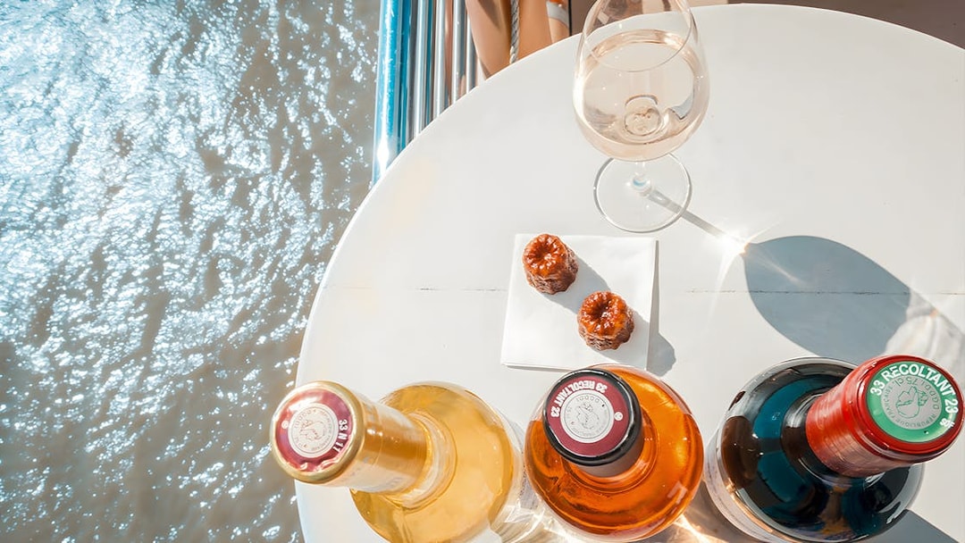 Bottles of wine and canelés on a table during Bordeaux River Cruise.