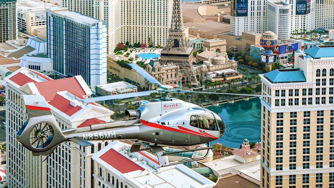 Maverick Helicopter flying over the Las Vegas Strip with city landmarks below.