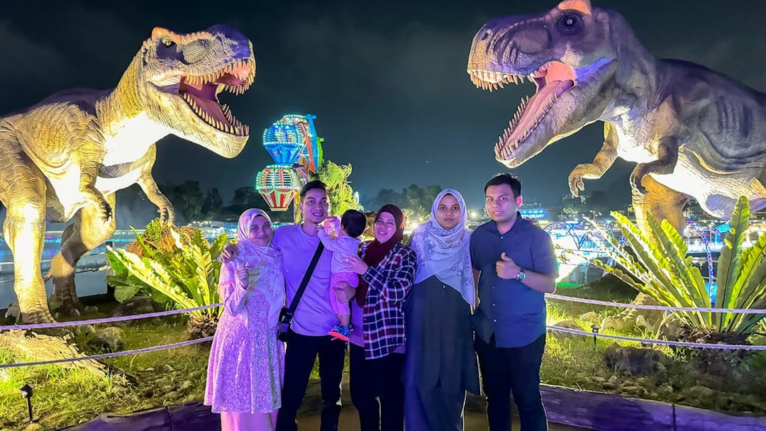 Group posing with dinosaur statues at night in 99 Wonderland Park.