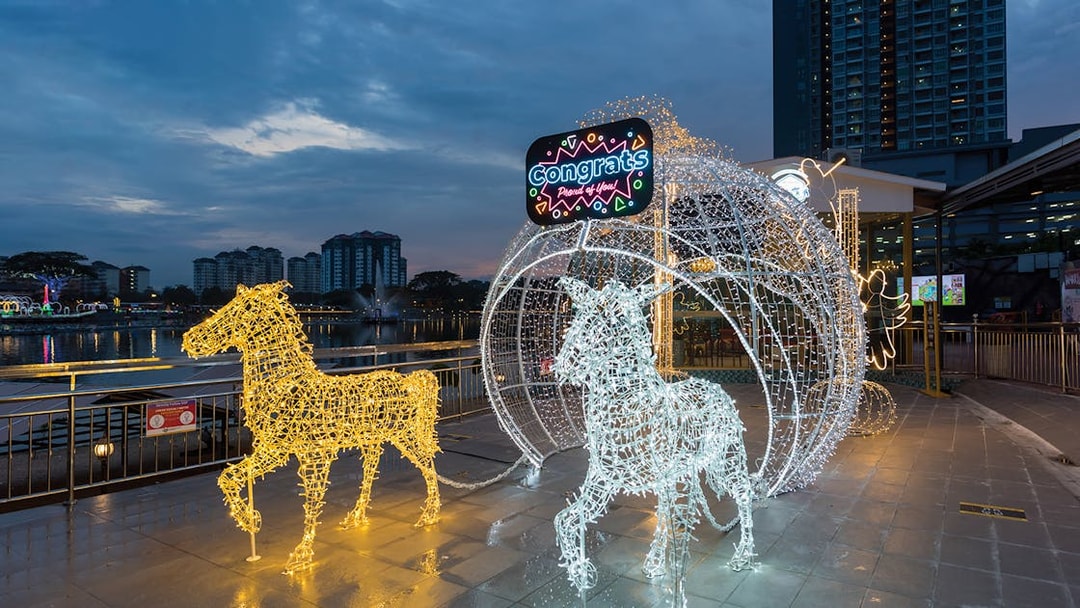 Illuminated horse sculptures at 99 Wonderland Park, Kuala Lumpur, with city skyline in the background.