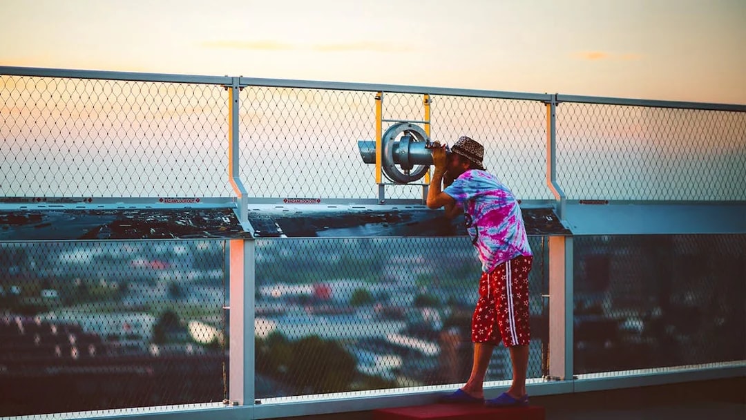 Person using a telescope at ADAM Lookout deck in Amsterdam.