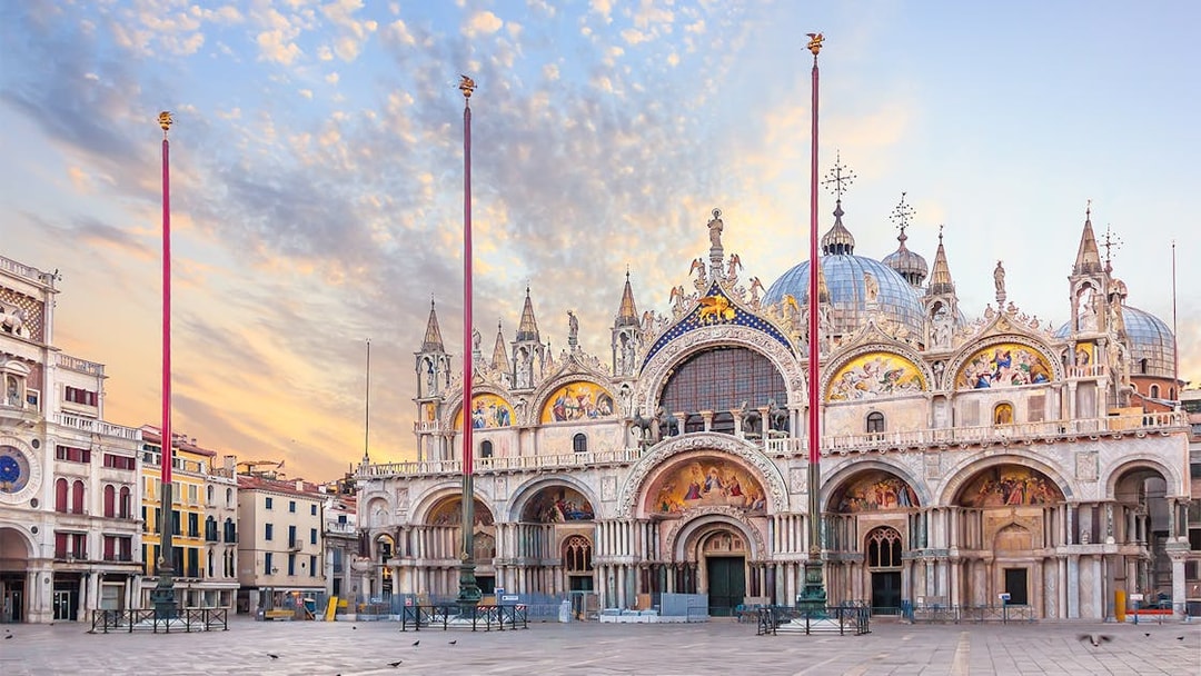 St. Mark's Basilica facade at sunrise in Venice, Italy, showcasing intricate mosaics and architecture.
