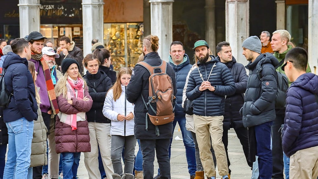 Group of tourists listening to a guide during a walking tour in Venice.