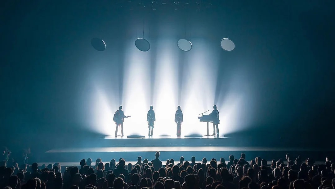 Silhouetted performers on stage with audience at ABBA Voyage show in London.