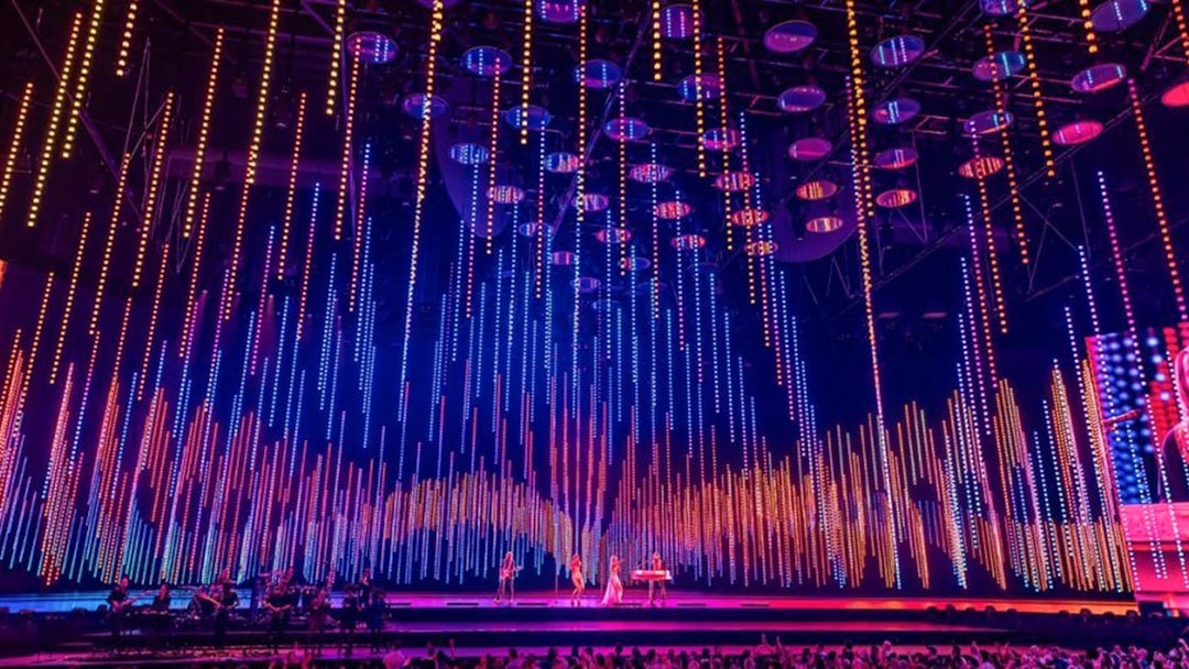 ABBA Voyage concert stage with colorful light display and audience.