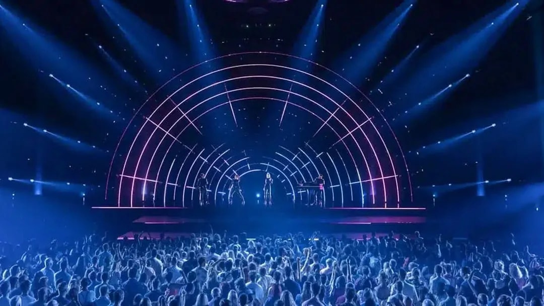 Crowd watching ABBA Voyage concert with illuminated stage and performers.