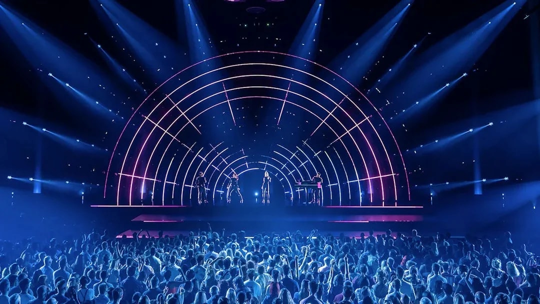 Crowd enjoying ABBA Voyage concert with vibrant stage lights in London.