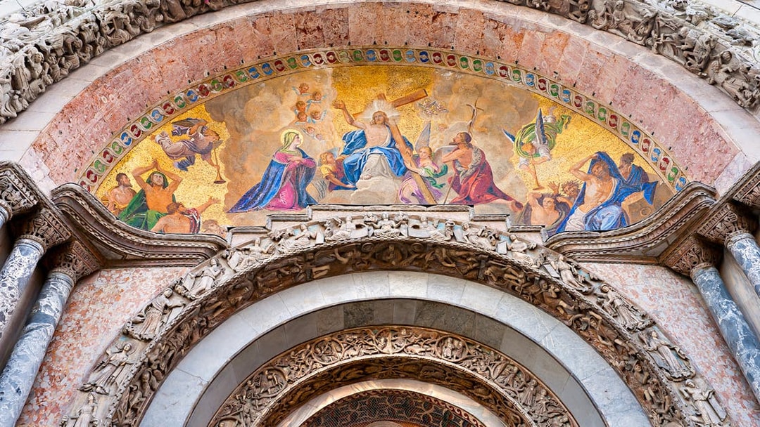 Mosaic detail above entrance of St Mark's Basilica, Venice, featuring religious figures and intricate carvings.