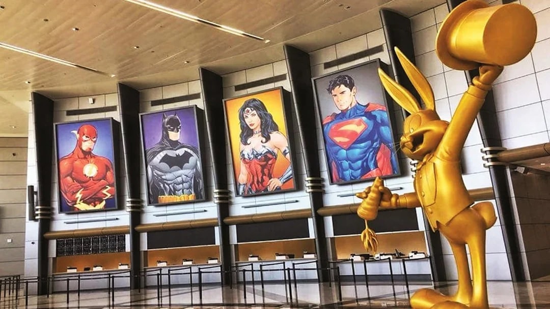 Warner Bros. Abu Dhabi entrance with superhero posters and golden cartoon statue.