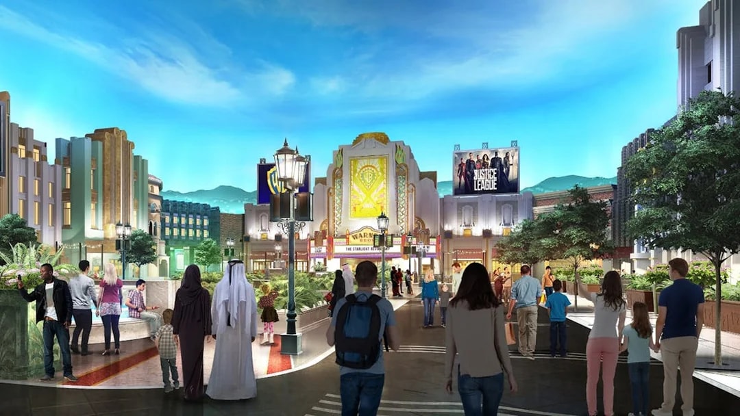 Visitors walking through Warner Bros. World Abu Dhabi with themed buildings and Justice League sign.