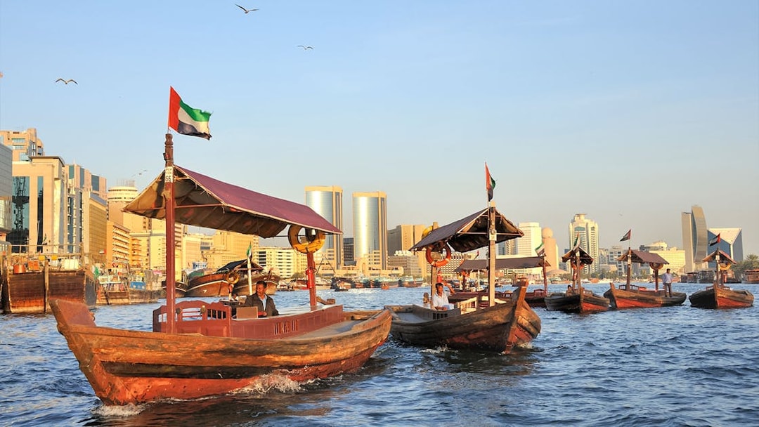Traditional wooden boats on Dubai Creek with city skyline in the background.